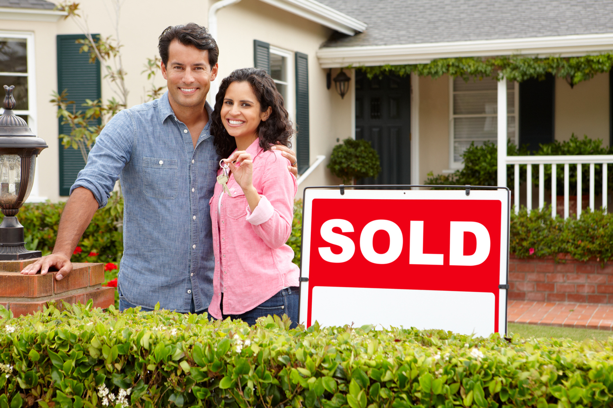 Happy couple showing off their sold house after having help purchasing thanks to real estate attorneys in Central Illinois