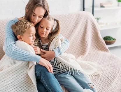 A mother needing help from Essig Law Office, which practices family law in the Peoria IL area, wraps her kids in her arms after a child custody case